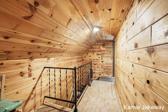 hallway featuring vaulted ceiling, wood walls, and wood ceiling