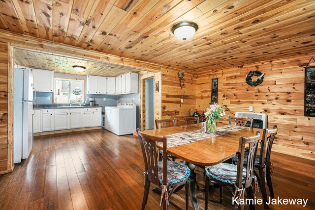 dining room featuring dark hardwood / wood-style floors, wood ceiling, wooden walls, sink, and washer / clothes dryer