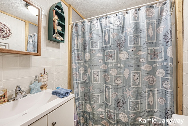 bathroom with toilet, a textured ceiling, vanity, and tile walls