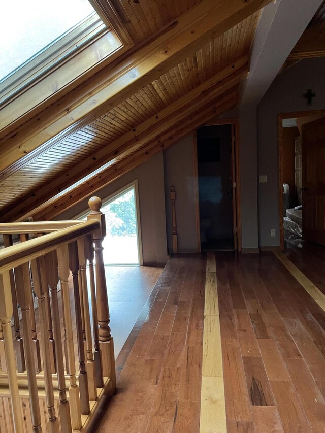 hallway with vaulted ceiling with skylight, wooden ceiling, and hardwood / wood-style floors