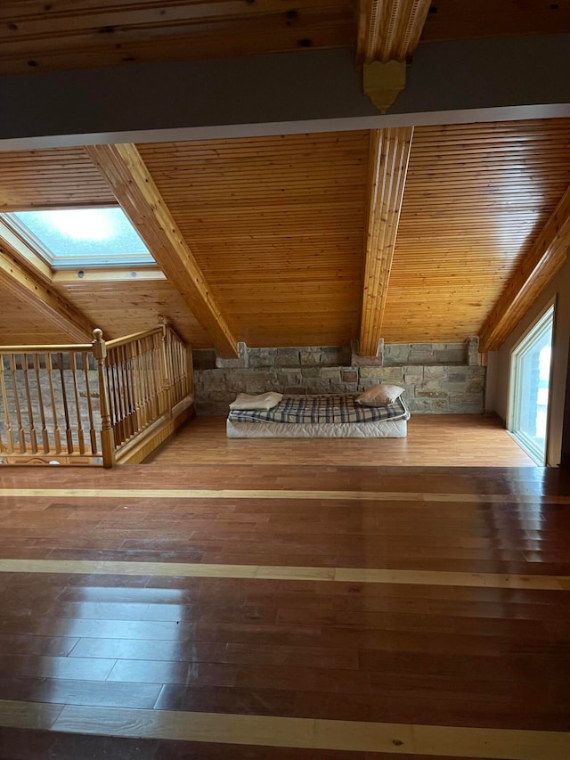 additional living space with beamed ceiling, a skylight, hardwood / wood-style floors, and wood ceiling