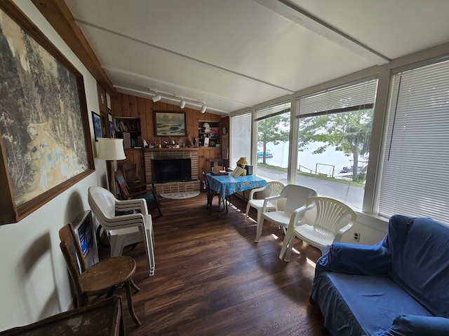 sunroom featuring a brick fireplace and lofted ceiling