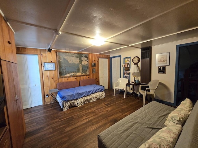 bedroom with dark wood-type flooring and wooden walls