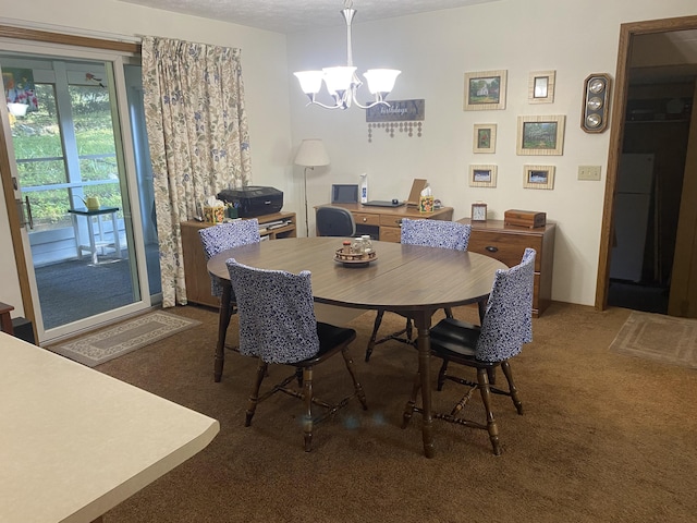 dining space with a chandelier, dark carpet, and a textured ceiling