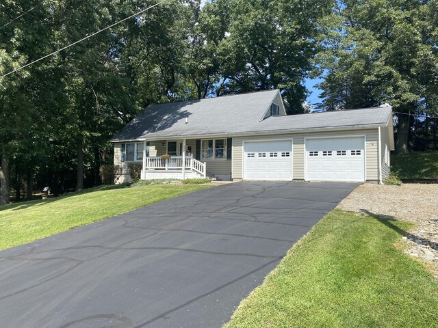 view of front of home with covered porch, driveway, a front lawn, and a garage