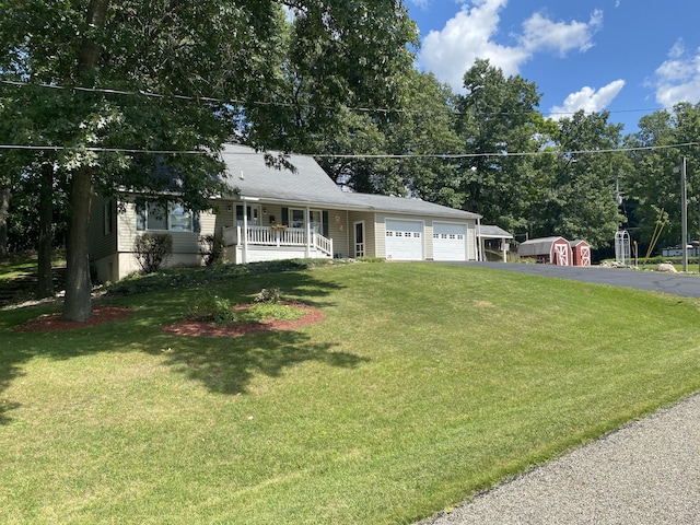 ranch-style house with an outbuilding, aphalt driveway, an attached garage, covered porch, and a front yard