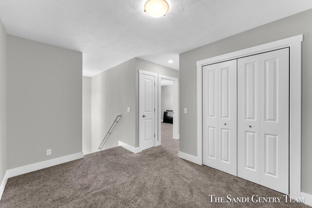 unfurnished bedroom featuring a closet, a textured ceiling, and carpet