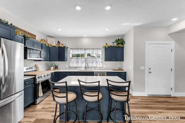 kitchen featuring light hardwood / wood-style flooring, sink, stainless steel appliances, and a center island