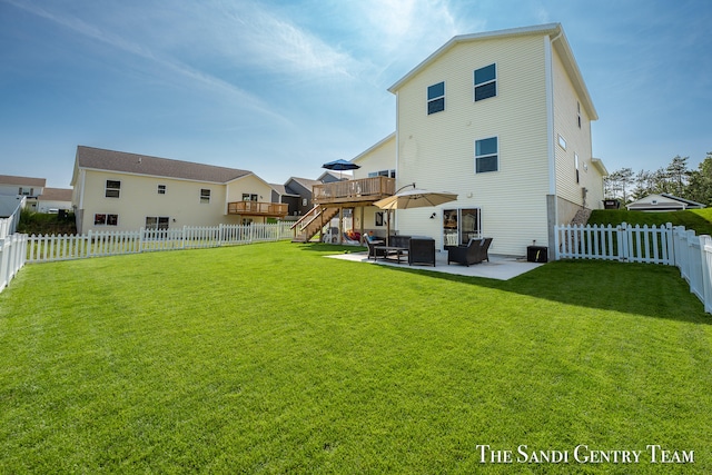 rear view of property featuring a patio area, a yard, and a wooden deck