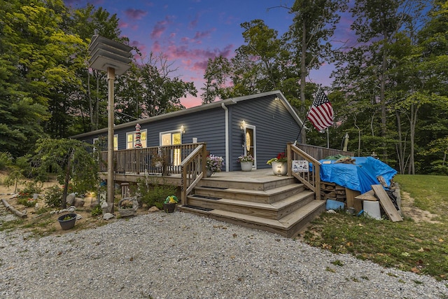 back house at dusk featuring a deck