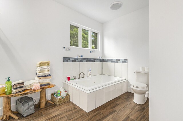 bathroom featuring a tub to relax in, wood-type flooring, and toilet