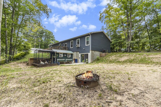 rear view of property featuring a deck and an outdoor fire pit