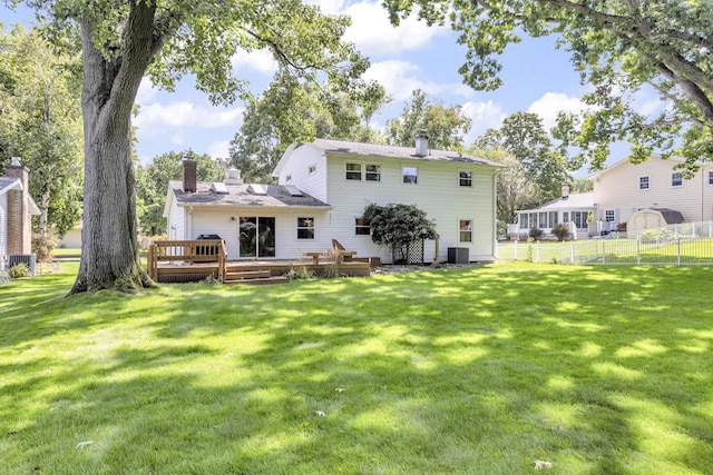 back of property featuring a yard, a chimney, central air condition unit, fence, and a wooden deck