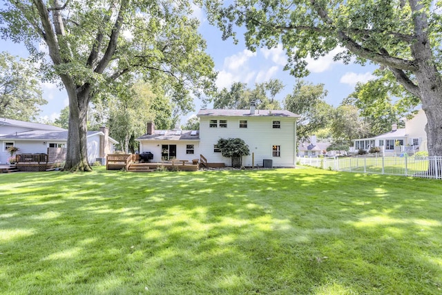 rear view of house featuring a yard, a wooden deck, and fence