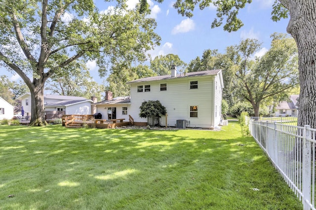 back of property with a fenced backyard, a chimney, a wooden deck, and a yard