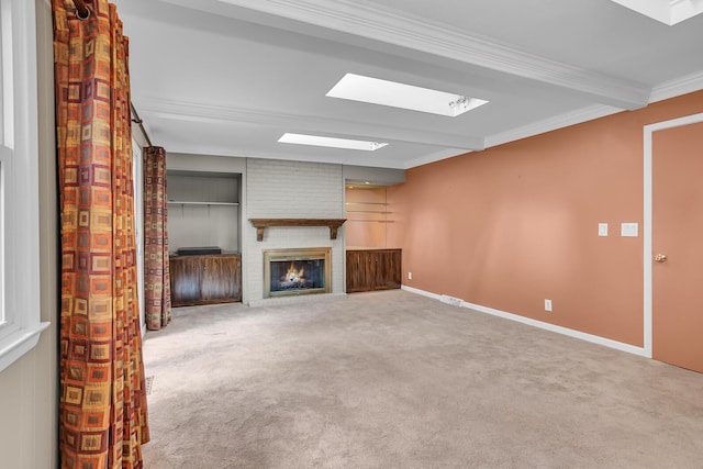 unfurnished living room with carpet floors, a fireplace, a skylight, baseboards, and crown molding