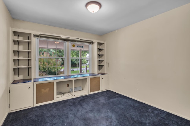 unfurnished office featuring dark carpet and baseboards