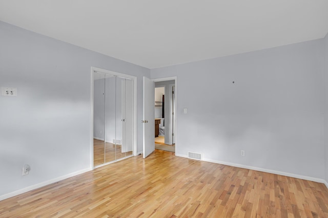 empty room with light wood finished floors, baseboards, and visible vents