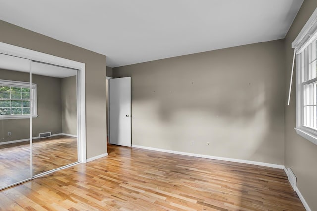 unfurnished bedroom featuring light wood-style flooring, multiple windows, and visible vents