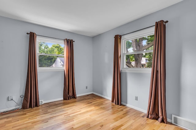 spare room with a wealth of natural light, baseboards, visible vents, and light wood finished floors