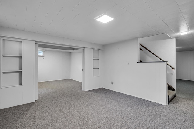 basement featuring built in features, dark colored carpet, and stairway