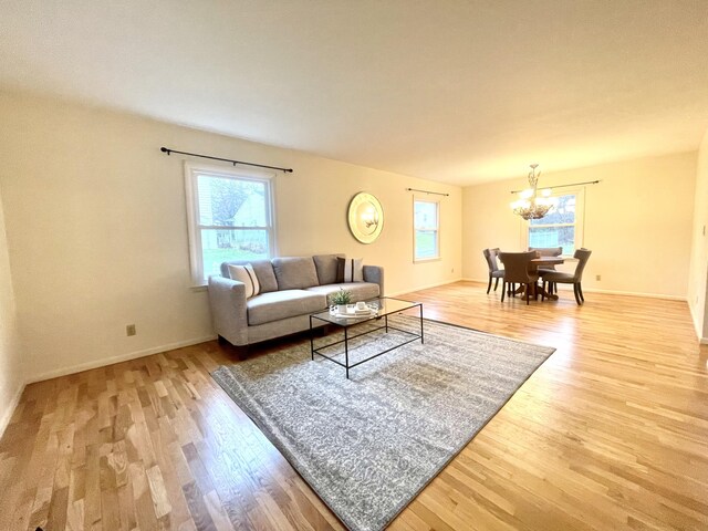 living room featuring a wealth of natural light, a notable chandelier, baseboards, and wood finished floors