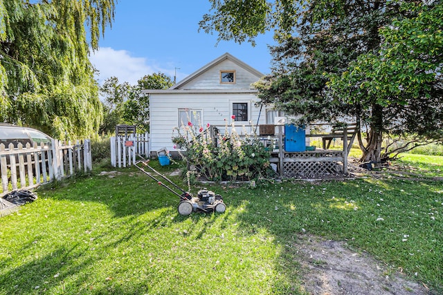 rear view of property featuring a deck and a lawn