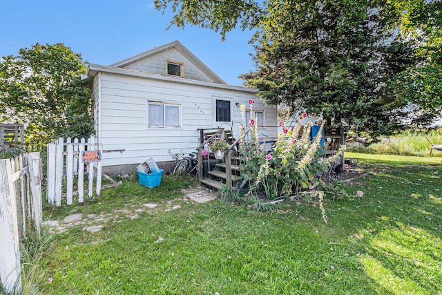 rear view of house with a lawn and fence