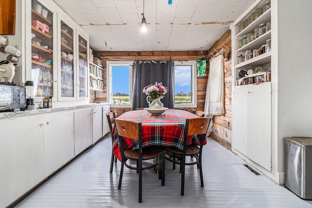 dining area with light wood-type flooring and wooden walls