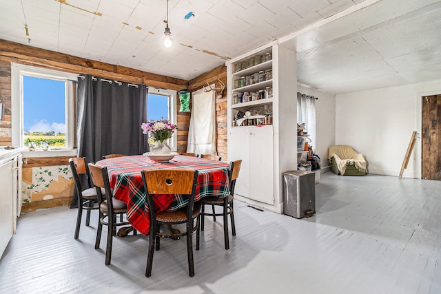 dining space with light wood-type flooring and wood walls