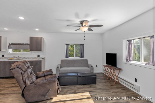 living room with ceiling fan, a baseboard heating unit, dark hardwood / wood-style flooring, and sink