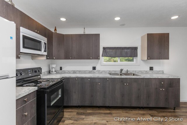 kitchen with sink, dark brown cabinets, dark hardwood / wood-style floors, and white appliances