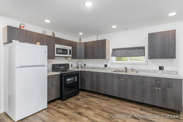 kitchen with dark hardwood / wood-style floors, sink, white appliances, and dark brown cabinets