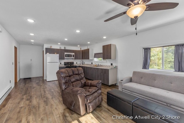 living room featuring a baseboard heating unit, ceiling fan, light hardwood / wood-style flooring, and sink