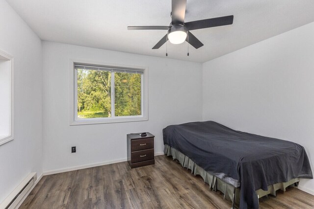 bedroom with a baseboard heating unit, ceiling fan, and dark hardwood / wood-style flooring