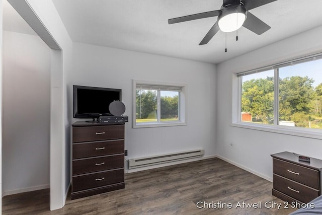 bedroom with ceiling fan, multiple windows, a baseboard heating unit, and dark hardwood / wood-style flooring