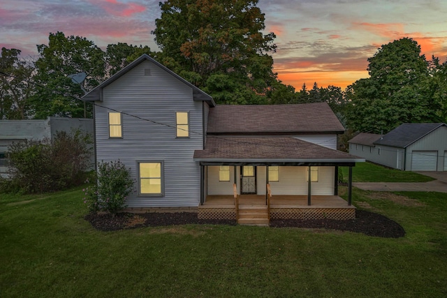 view of front of property with a porch, a garage, a yard, and an outbuilding