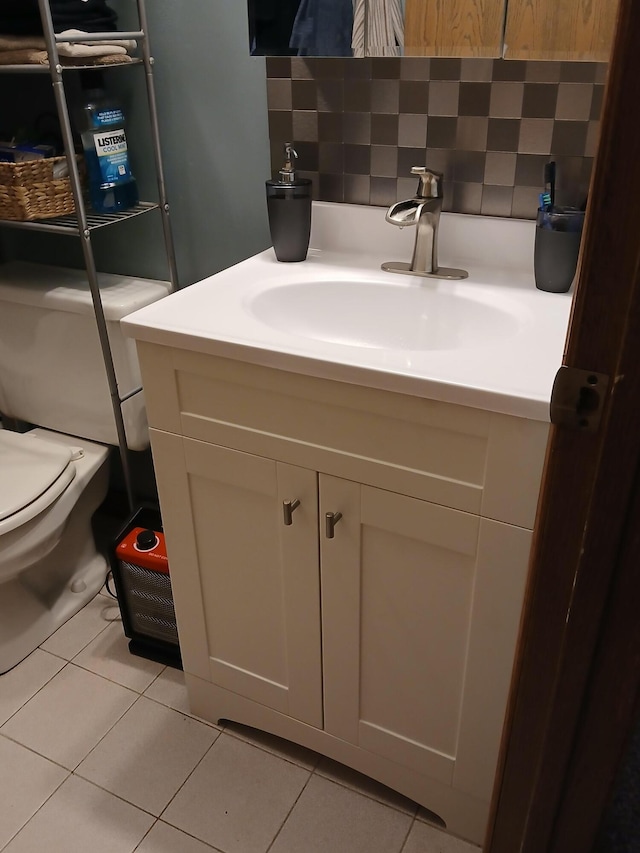 half bathroom with tile patterned floors, tasteful backsplash, vanity, and toilet