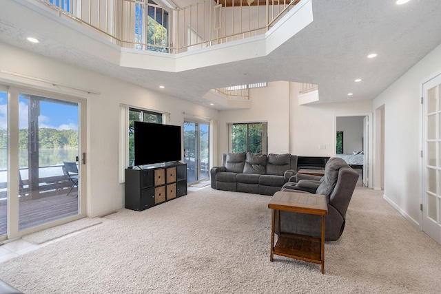 carpeted living room featuring plenty of natural light and a high ceiling