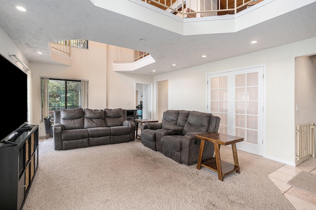 living room with light carpet, a textured ceiling, and a high ceiling