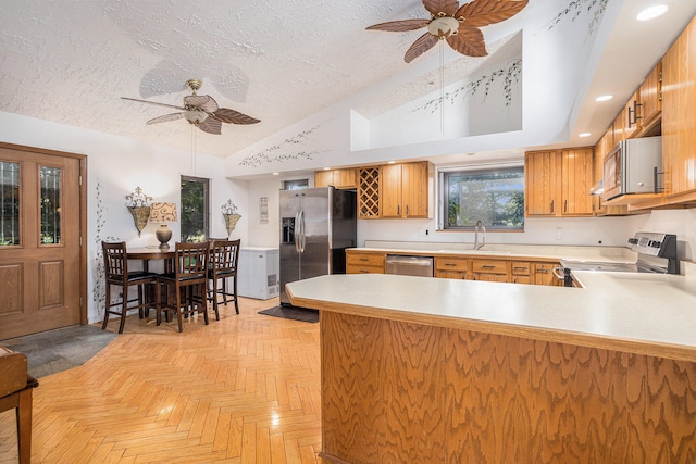 kitchen featuring light parquet floors, stainless steel appliances, kitchen peninsula, and ceiling fan