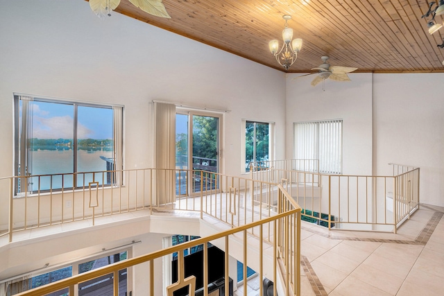 corridor featuring a notable chandelier, a water view, light tile patterned floors, and wooden ceiling