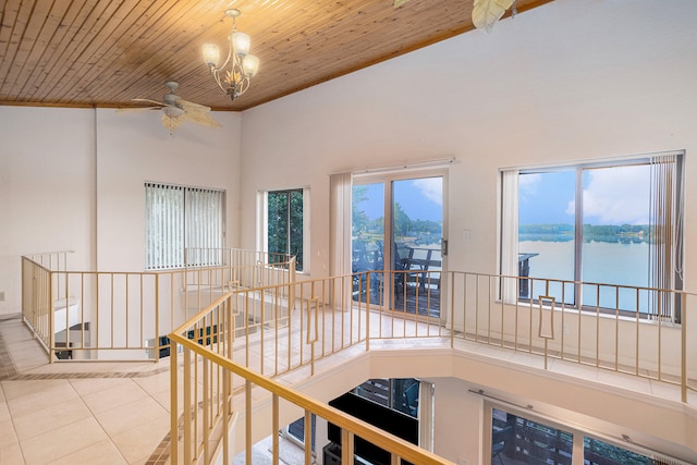 hall with high vaulted ceiling, light tile patterned flooring, a chandelier, a water view, and wood ceiling