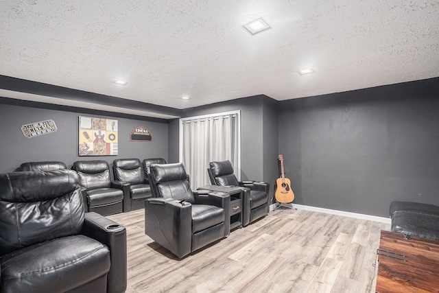 home theater room featuring light wood-type flooring and a textured ceiling