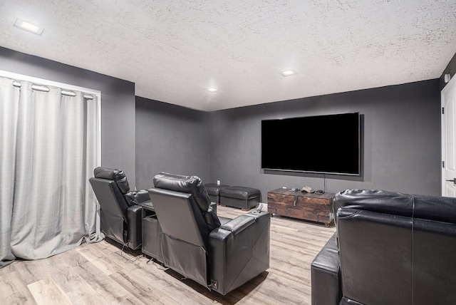 cinema featuring light wood-type flooring and a textured ceiling