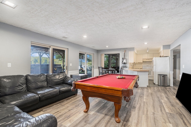 recreation room with sink, light wood-type flooring, a textured ceiling, and billiards