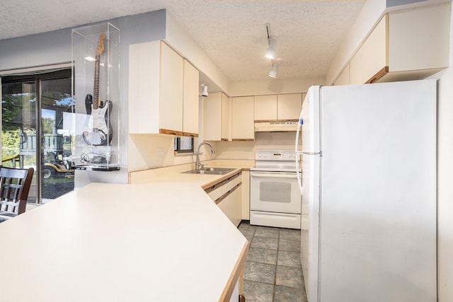 kitchen featuring white appliances, a textured ceiling, rail lighting, dark tile patterned floors, and sink