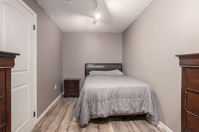 bedroom with light wood-type flooring and a textured ceiling