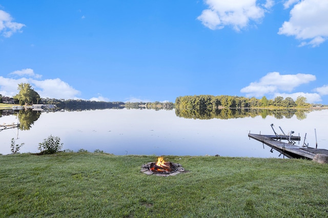 view of dock with a yard, a water view, and a fire pit