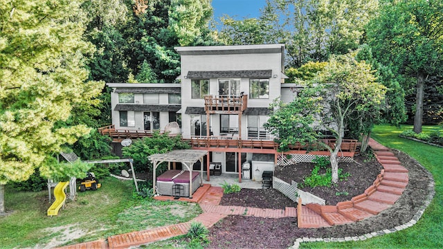 rear view of property featuring a wooden deck, a playground, and a yard